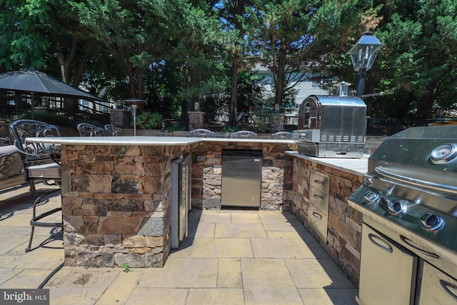 view of patio with area for grilling, an outdoor kitchen, and outdoor wet bar