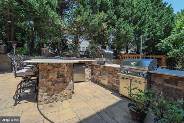view of patio / terrace featuring area for grilling, a grill, outdoor wet bar, and fence