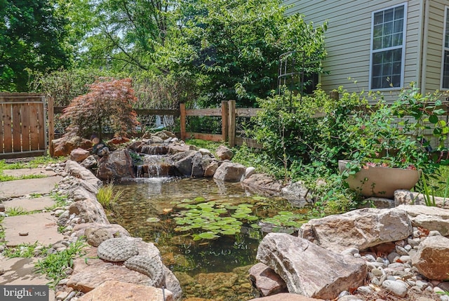 view of yard featuring a small pond and fence