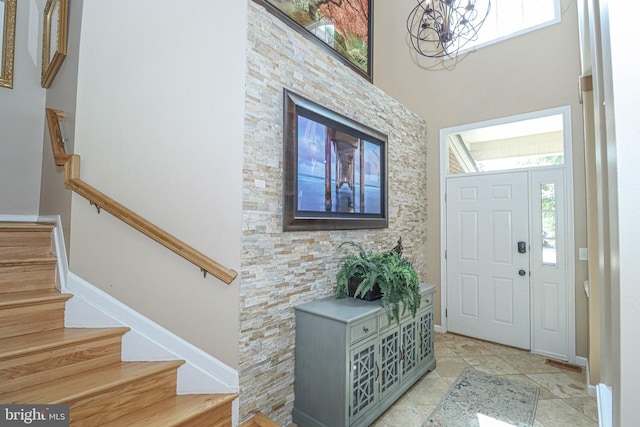 foyer entrance with a towering ceiling, stairs, and baseboards