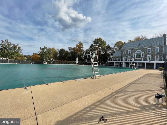 view of swimming pool with community basketball court and fence