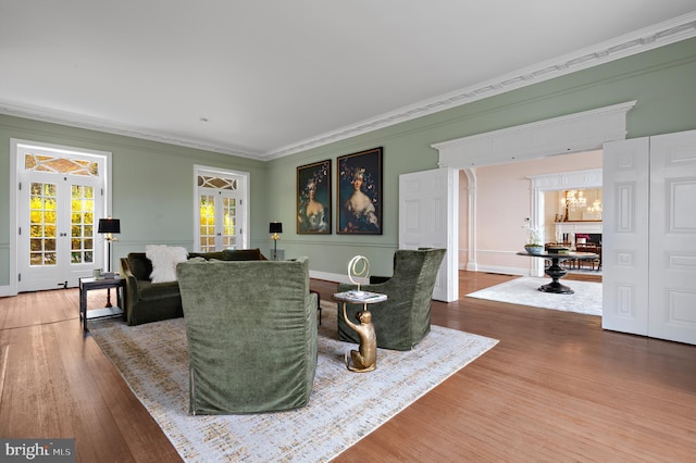living room featuring crown molding, french doors, wood finished floors, and an inviting chandelier