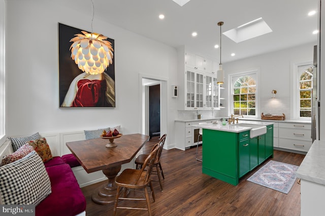 kitchen featuring tasteful backsplash, a skylight, a kitchen island with sink, and dark wood-style floors