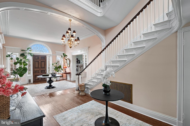 entrance foyer with a chandelier, wood-type flooring, baseboards, and stairs