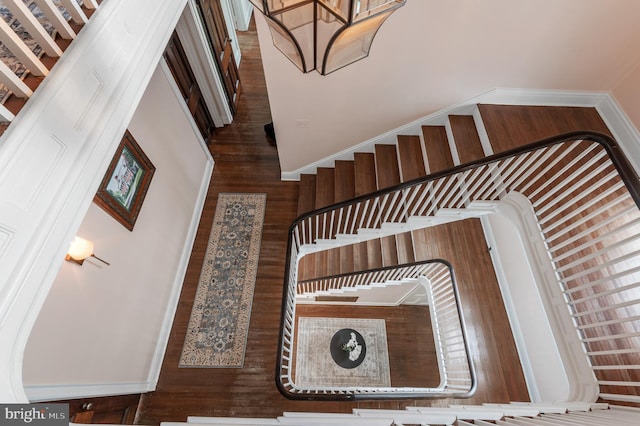 staircase with a chandelier and wood finished floors