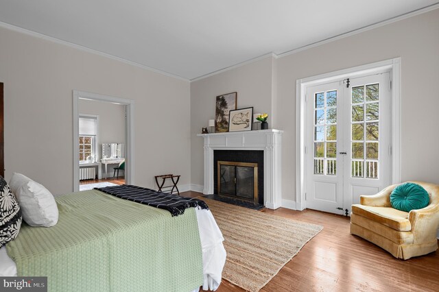 bedroom with a fireplace with flush hearth, multiple windows, crown molding, and wood finished floors