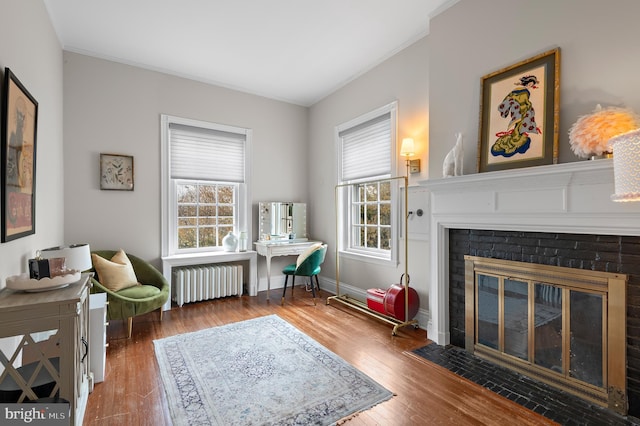 living area featuring crown molding, wood finished floors, and radiator heating unit