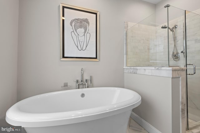 bathroom with a freestanding tub, marble finish floor, and a stall shower