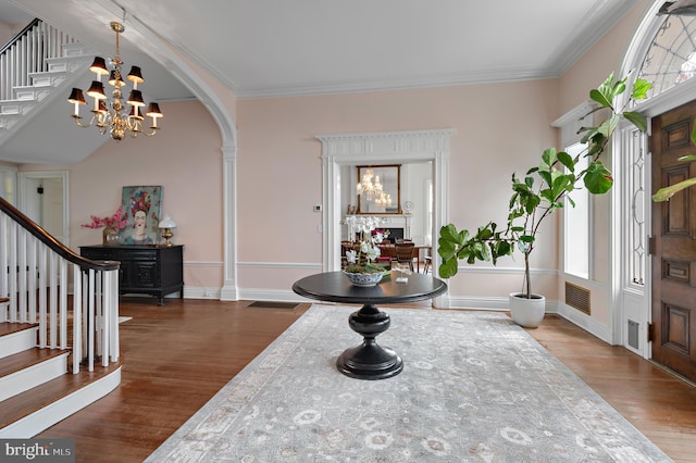 foyer entrance featuring visible vents, an inviting chandelier, wood finished floors, and stairs