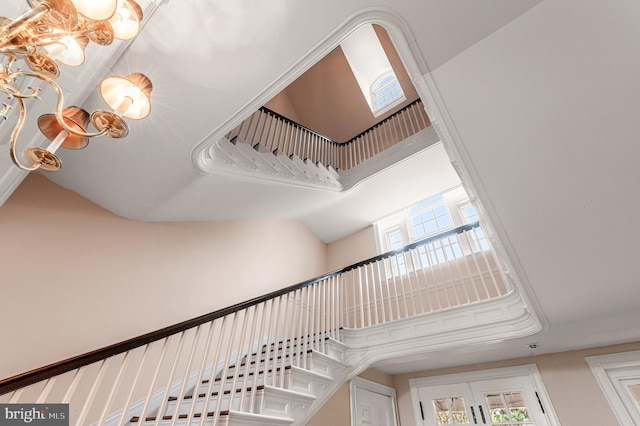 stairs with plenty of natural light, a chandelier, and a towering ceiling