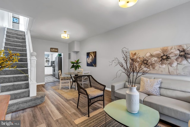 living area with stairway, wood finished floors, and baseboards