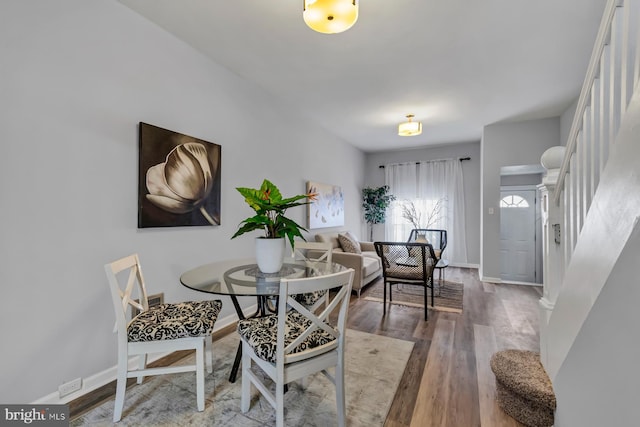 dining space with stairs, baseboards, and wood finished floors