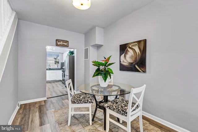 dining room featuring baseboards, visible vents, and wood finished floors