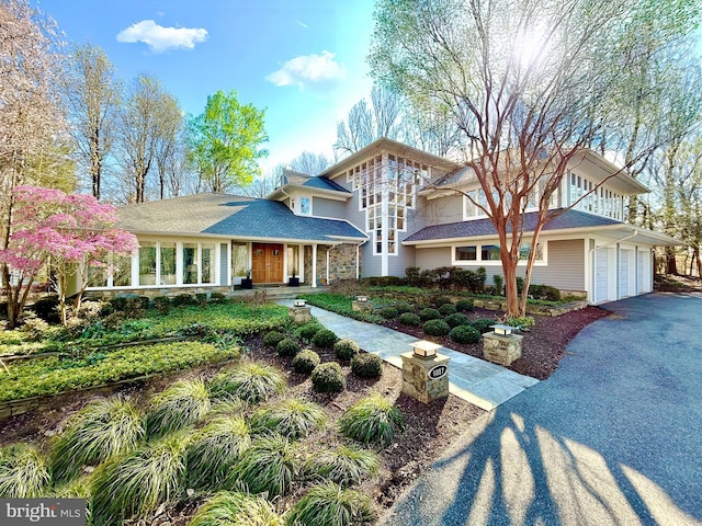 view of front of property featuring a garage, stone siding, and driveway