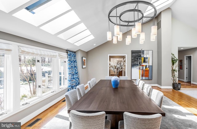 dining space with vaulted ceiling with skylight, visible vents, and light wood-style floors