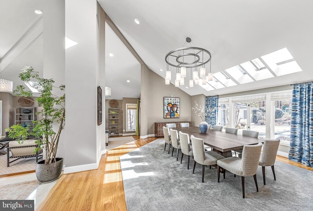 dining space featuring a skylight, light wood finished floors, recessed lighting, high vaulted ceiling, and baseboards