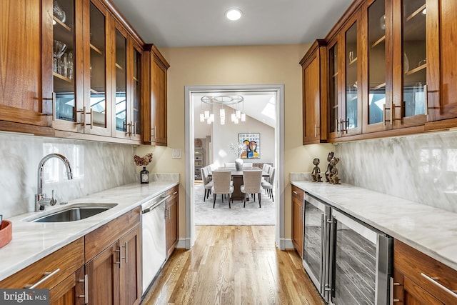 kitchen featuring brown cabinets, backsplash, stainless steel dishwasher, a sink, and beverage cooler