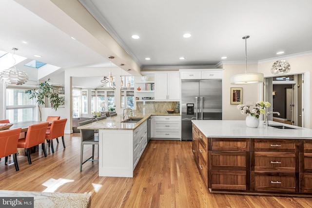 kitchen featuring crown molding, open shelves, stainless steel appliances, backsplash, and a sink