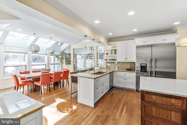 kitchen with stainless steel appliances, a peninsula, a skylight, white cabinetry, and open shelves