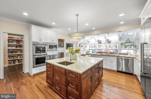 kitchen featuring white cabinetry, appliances with stainless steel finishes, a sink, and ornamental molding