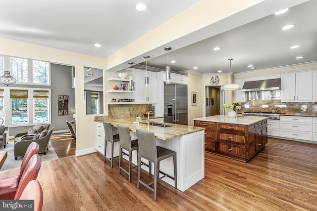 kitchen featuring a sink, wall chimney range hood, appliances with stainless steel finishes, dark wood-style floors, and open shelves