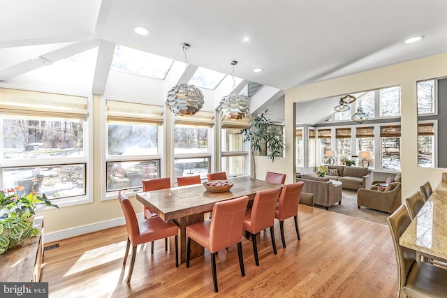 dining space featuring vaulted ceiling with skylight, light wood finished floors, plenty of natural light, and recessed lighting