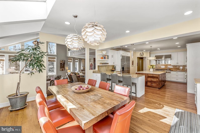 dining room with light wood-style floors, lofted ceiling, baseboards, and recessed lighting