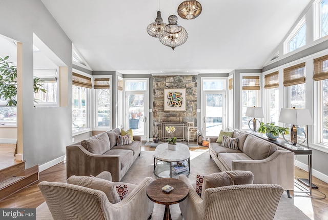 sunroom featuring a fireplace, a chandelier, and vaulted ceiling