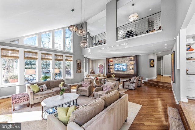 living area featuring high vaulted ceiling, an inviting chandelier, baseboards, and wood finished floors