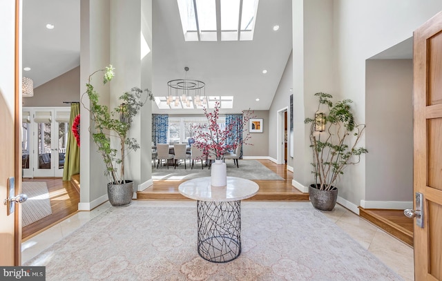 tiled foyer entrance featuring recessed lighting, a skylight, a towering ceiling, and baseboards