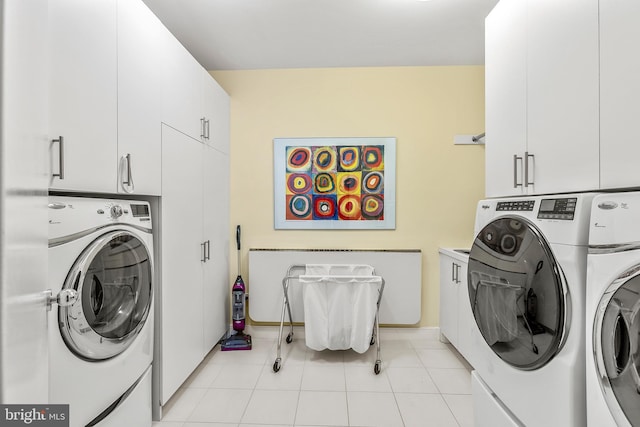 washroom featuring cabinet space, washer and clothes dryer, and light tile patterned flooring