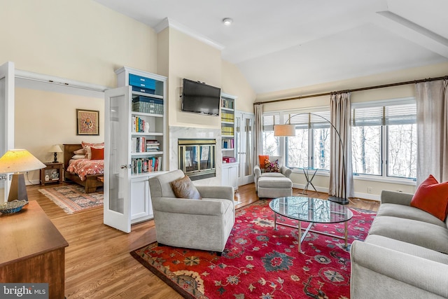 living area with lofted ceiling, a premium fireplace, baseboards, and wood finished floors