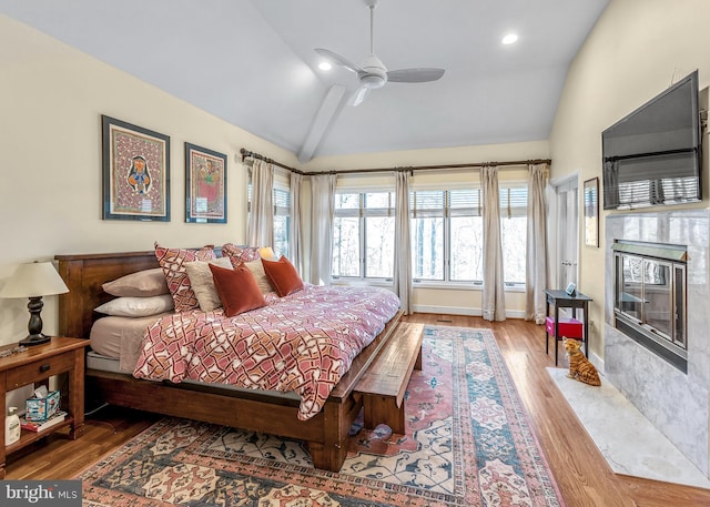 bedroom with baseboards, a premium fireplace, wood finished floors, vaulted ceiling, and recessed lighting