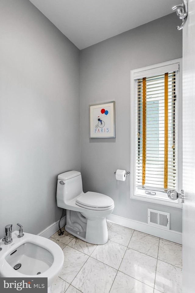 bathroom with a healthy amount of sunlight, marble finish floor, baseboards, and visible vents