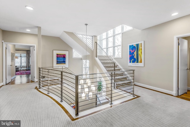 hall with baseboards, an upstairs landing, and recessed lighting