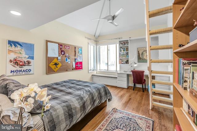 bedroom featuring vaulted ceiling, built in desk, and light wood-type flooring