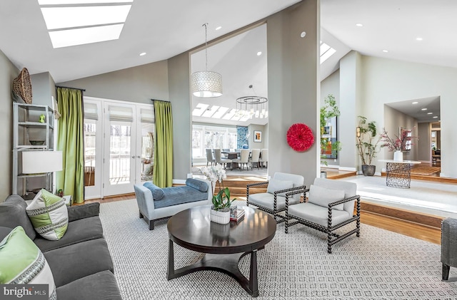 living room featuring high vaulted ceiling, a skylight, and wood finished floors