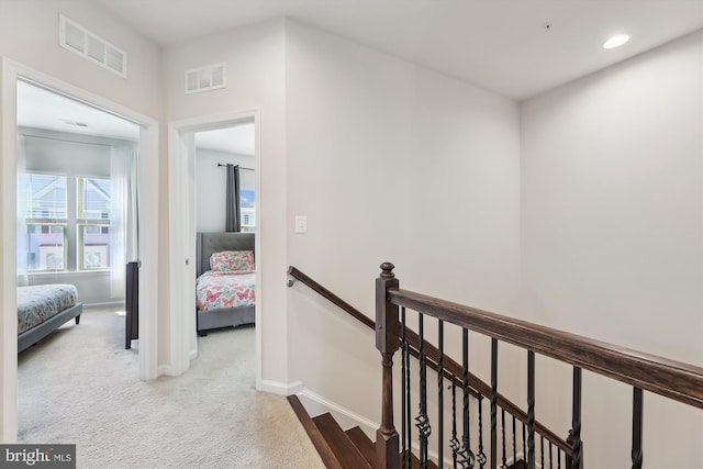 corridor featuring an upstairs landing, visible vents, and baseboards