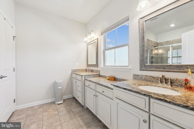 bathroom with a stall shower, tile patterned flooring, baseboards, and vanity