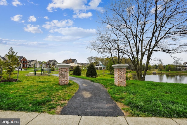 surrounding community with a residential view, a water view, a yard, and driveway