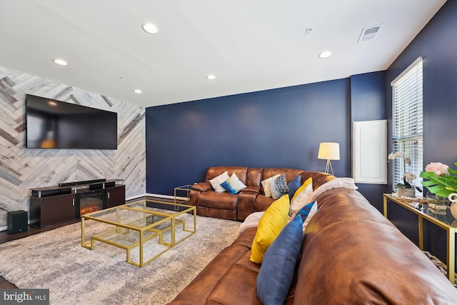 living area with an accent wall, visible vents, a fireplace, and recessed lighting