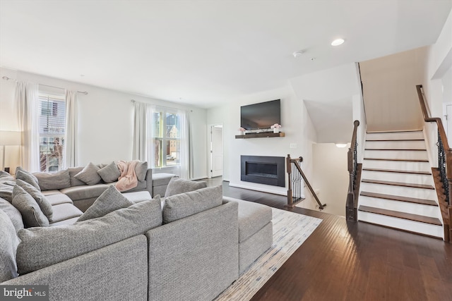 living area with recessed lighting, a glass covered fireplace, dark wood finished floors, and stairway