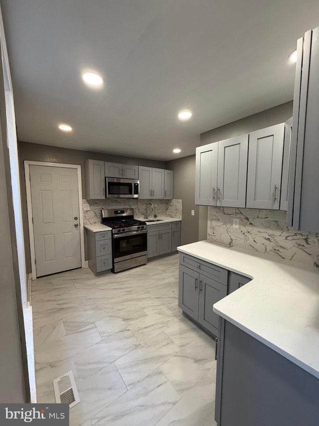 kitchen featuring visible vents, appliances with stainless steel finishes, marble finish floor, gray cabinetry, and a sink