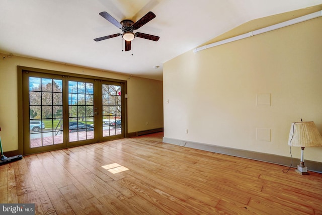 empty room with french doors, a baseboard radiator, light wood-style flooring, vaulted ceiling, and baseboards