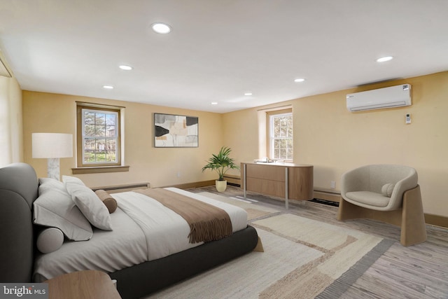 bedroom with light wood-type flooring, recessed lighting, baseboards, and a wall mounted AC