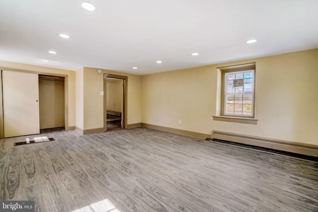 interior space featuring a baseboard heating unit, recessed lighting, light wood-style flooring, and baseboards