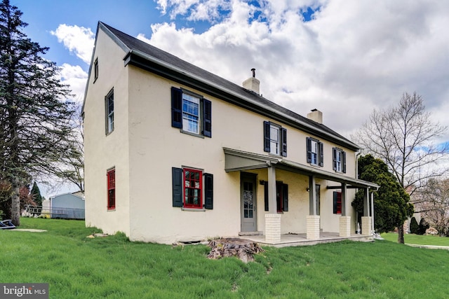 view of front of home with a chimney, a front lawn, and stucco siding