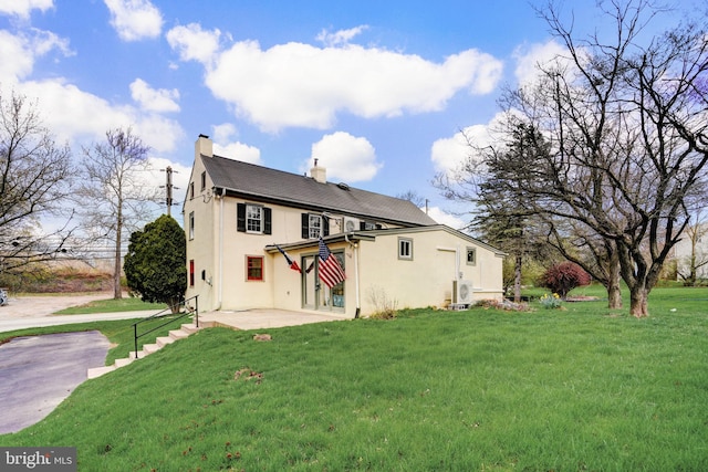 back of house featuring a chimney, a lawn, stucco siding, ac unit, and a patio area