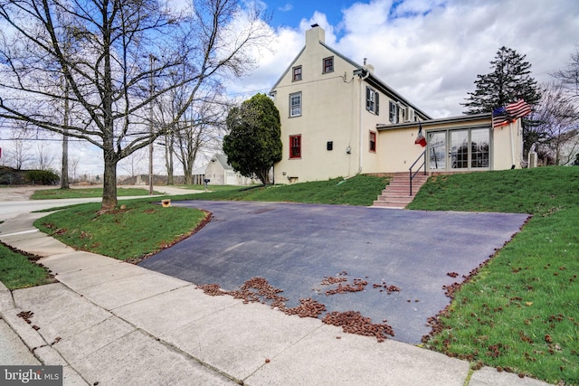 view of side of property with a yard, a chimney, and stucco siding