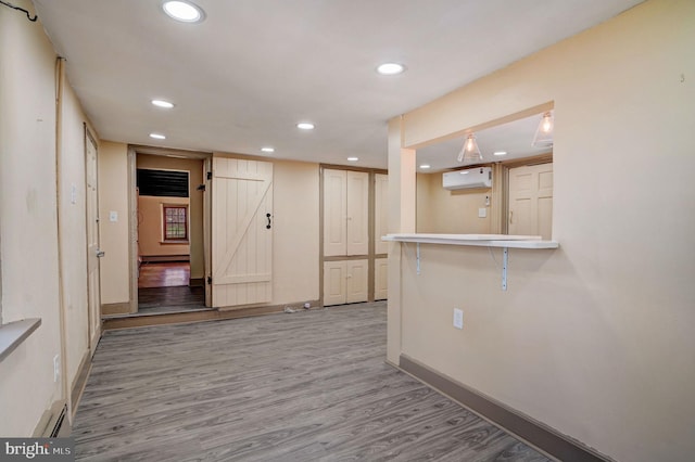 interior space featuring a barn door, baseboards, an AC wall unit, light wood-style floors, and recessed lighting